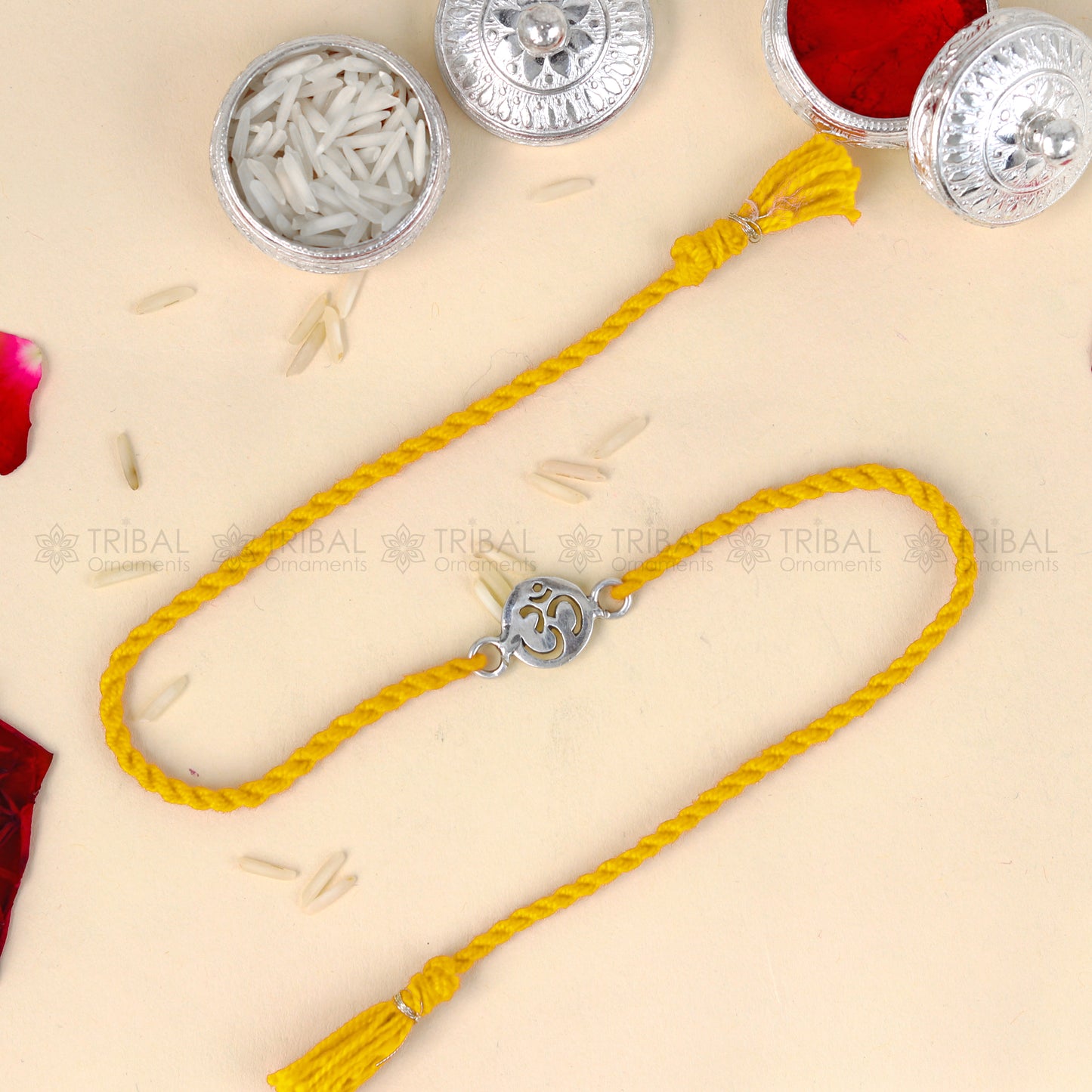 925 Sterling silver OM design thread rakhi bracelet with red thread from TRIBAL ORNAMENTS, featuring a detailed silver OM pendant.