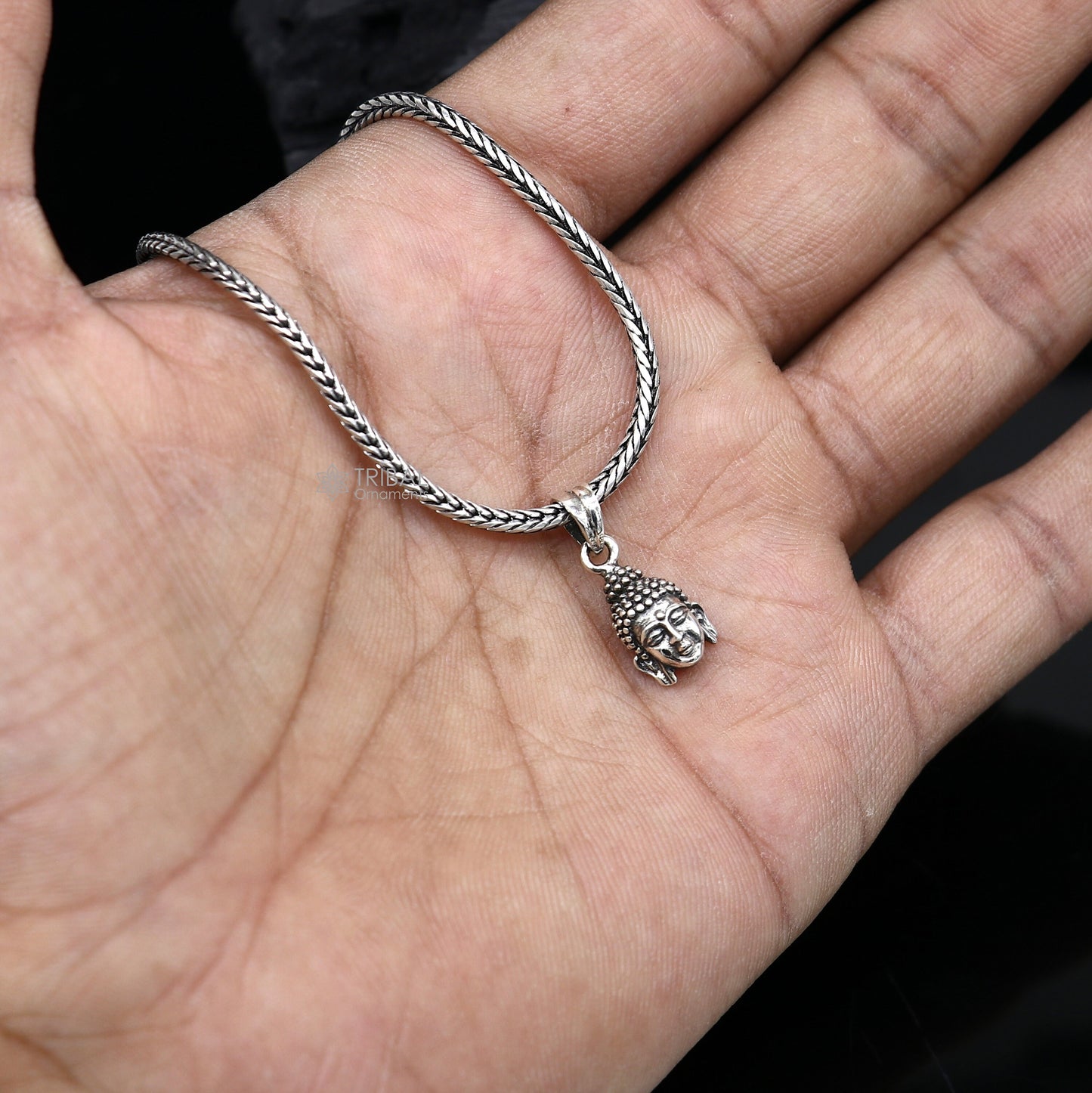 925 silver Lord Buddha face pendant by TRIBAL ORNAMENTS, close-up view showing intricate Buddha facial details and smooth silver finish.