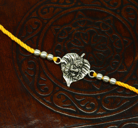 Sterling silver Krishna design bracelet with yellow thread rakhi, featuring Lord Krishna and Laddu Gopal motifs, by Tribal Ornaments.