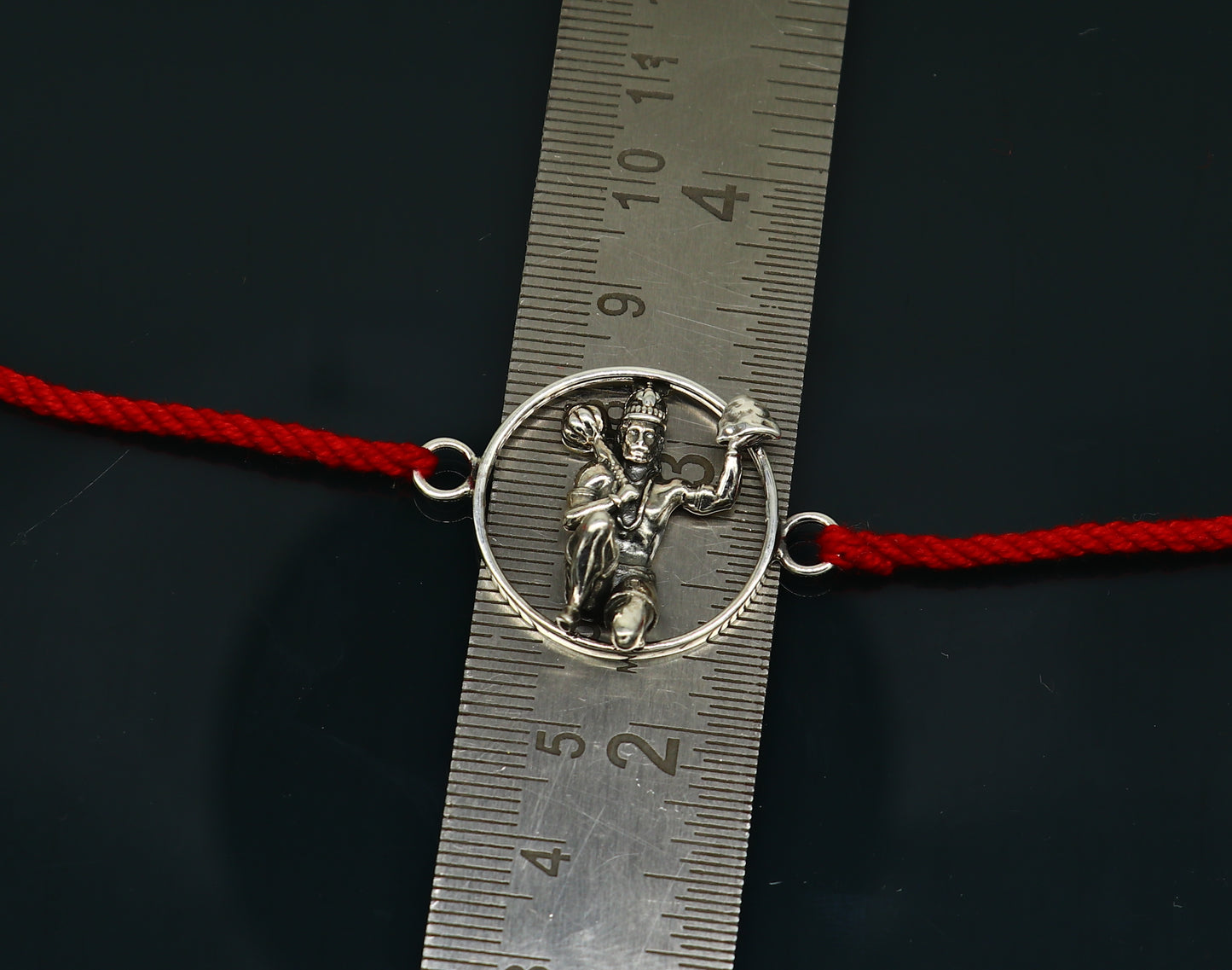 Sterling silver Hanuman idol bracelet with red thread rakhi, featuring intricate tribal design and craftsmanship by Tribal Ornaments.