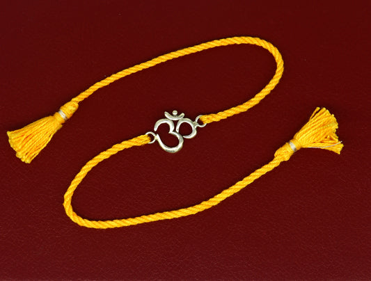 925 silver OM design bracelet with yellow thread rakhi, featuring custom sterling silver craftsmanship and intricate Aum motif.