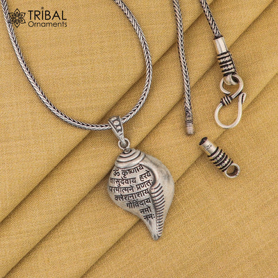 Close-up of a silver beaded necklace from Tribal Ornaments featuring an intricate pendant of a multi-armed Hindu deity seated in a traditional pose, set against a black fabric background.