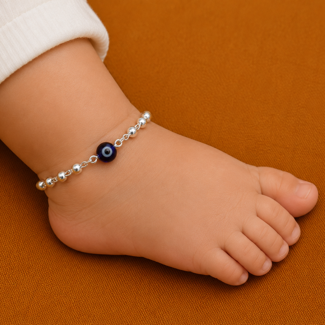 Child's foot wearing a silver evil eye anklet with blue bead, sterling silver beaded bracelet or anklet for girls and kids.