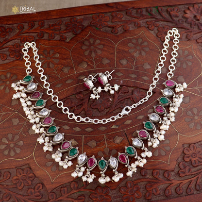 Sterling silver jewelry set with ruby red and green cut stones, including necklace and earrings, in oxidized tribal design.