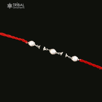 Sterling silver KARUNGALI and pearl beads Rakhi bracelet on red thread, crafted by TRIBAL ORNAMENTS, with intricate design details.
