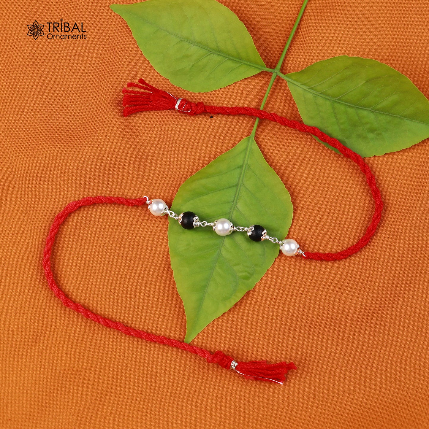 Sterling silver KARUNGALI and pearl beads Rakhi bracelet on red thread with intricate tribal design, crafted by TRIBAL ORNAMENTS.