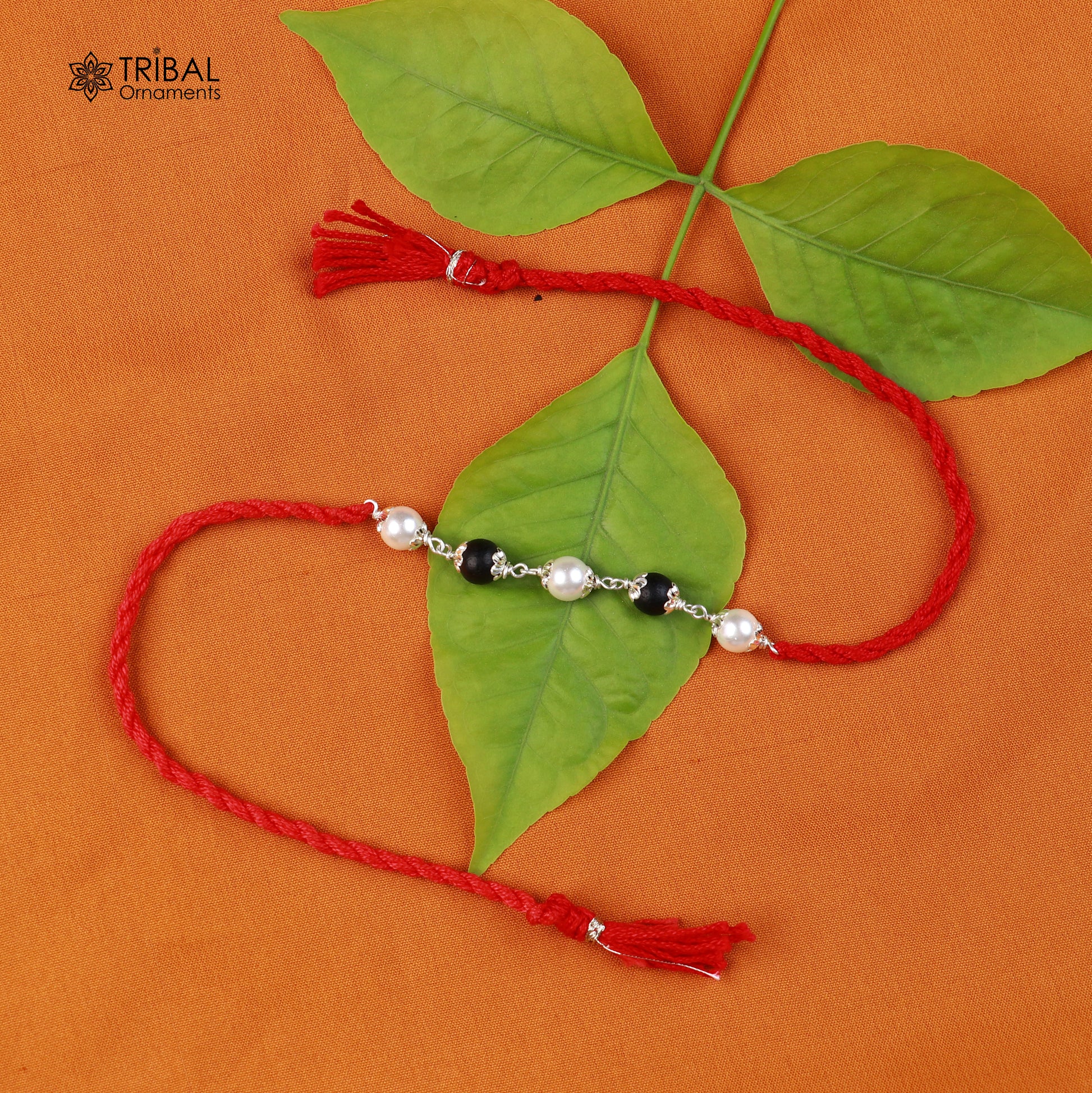 Sterling silver KARUNGALI and pearl beads Rakhi bracelet on red thread with intricate tribal design, crafted by TRIBAL ORNAMENTS.