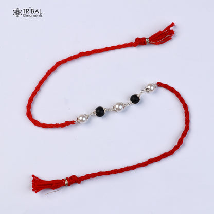 Sterling silver KARUNGALI and pearl bead Rakhi bracelet with red thread from TRIBAL ORNAMENTS, featuring intricate design.