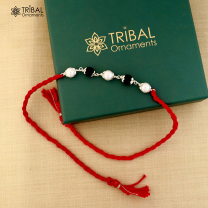 Sterling silver KARUNGALI and pearl beads Rakhi bracelet on red thread with intricate design, from TRIBAL ORNAMENTS.