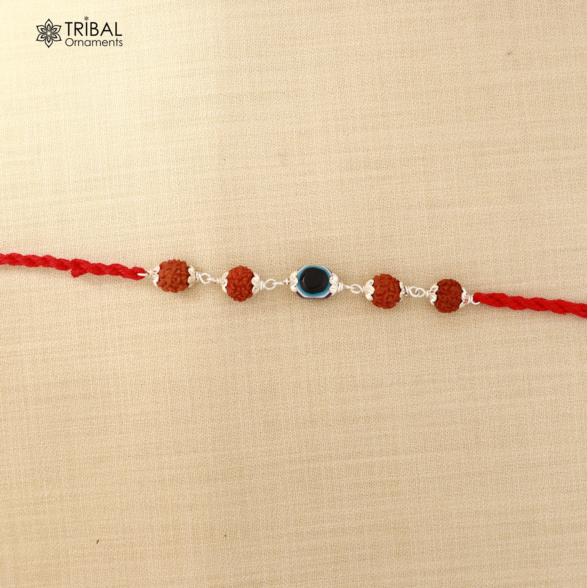 925 sterling silver Rakhi bracelet with Rudraksha and evil eye beads on red thread, from Tribal Ornaments.