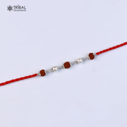 Sterling silver Rakhi bracelet with Rudraksha, pearl beads, and red thread, featuring intricate tribal ornament design.