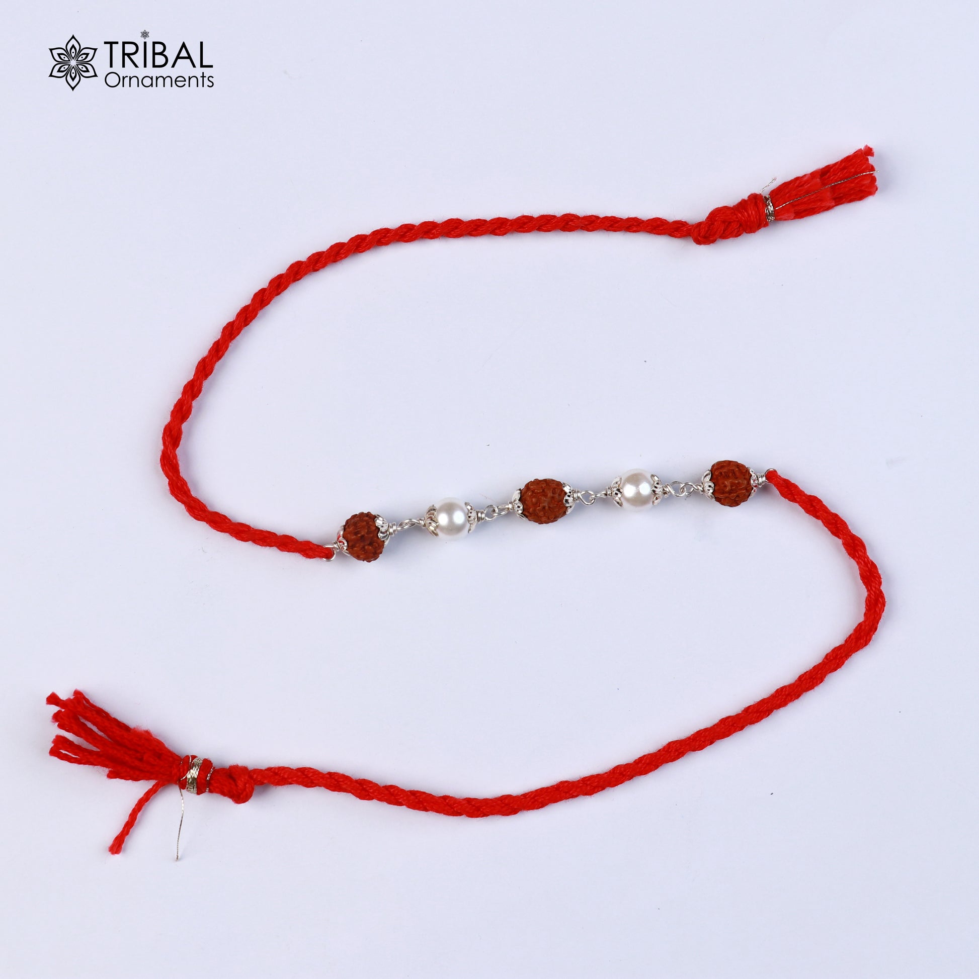 Sterling silver RUDRAKSHA and pearl beads Rakhi bracelet with red thread from TRIBAL ORNAMENTS, featuring intricate design details.