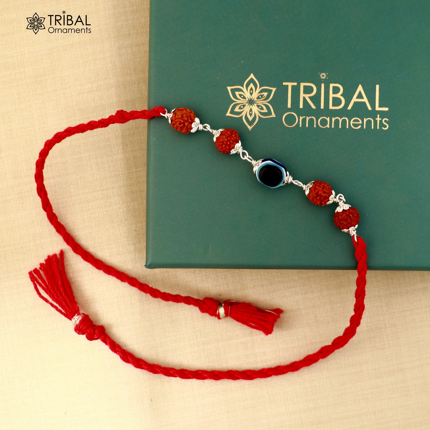 Sterling silver RUDRAKSHA and evil eye beads on red thread rakhi bracelet with intricate design by TRIBAL ORNAMENTS.