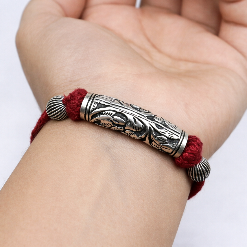 Sterling silver fancy charm bracelet with intricate design on red cord, stylish tribal jewelry for wedding and ethnic gifting