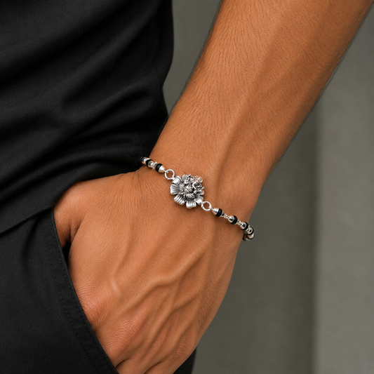 Sterling silver Lord Ganesha with floral design on black Tulsi beads bracelet, traditional Rakhi for festive celebrations.