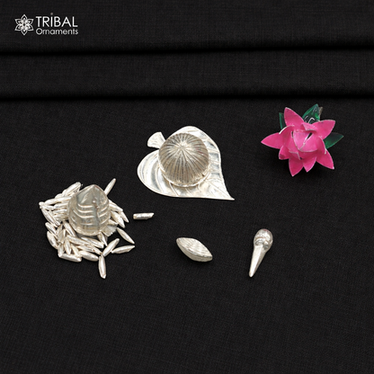 Sterling silver pooja accessories including supari, paan leaves, rice, cloves, coconut, cardamom, and flower for worship.