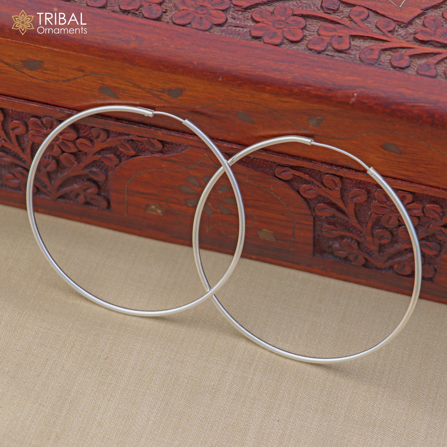 Sterling silver round hoop earrings by TRIBAL ORNAMENTS, showcasing elegant, polished jewelry design in close-up image.