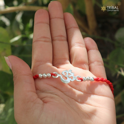 Sterling silver rakhi bracelet with custom OM/AUM symbol and red thread, crafted by TRIBAL ORNAMENTS.