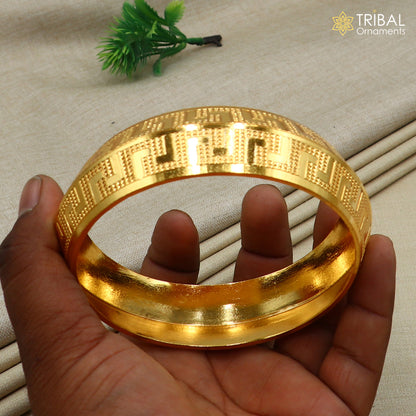 Stylish 999 pure silver gold-polished heavy bangle kada by TRIBAL ORNAMENTS, featuring intricate tribal design and shiny finish.