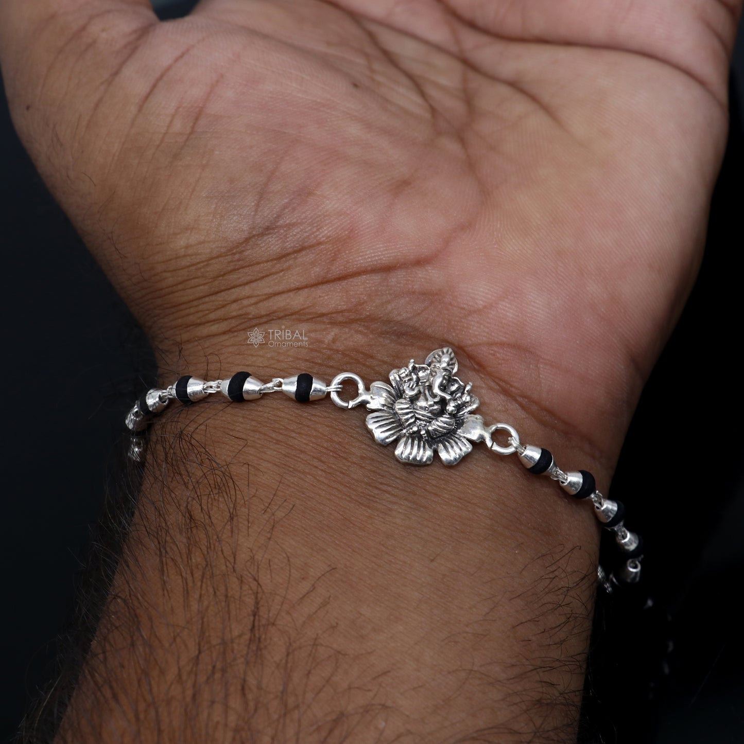 Sterling silver Lord Ganesha bracelet with flower design and black Tulsi beads, handmade Rakhi from Tribal Ornaments.