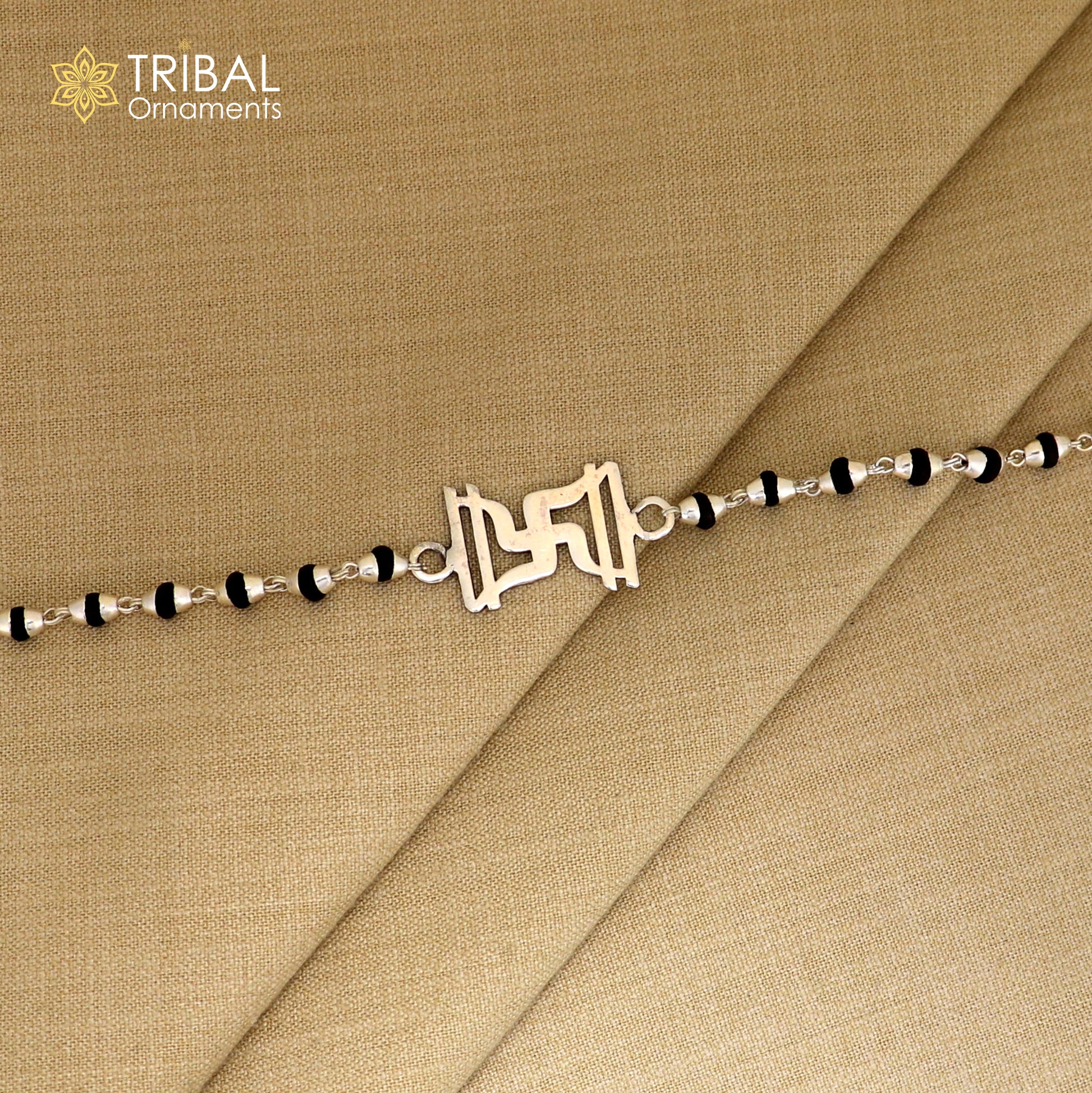 Sterling silver Swastik design Rudraksha and black tulsi beads bracelet rakhi with silver beads, intricate tribal ornament craftsmanship.
