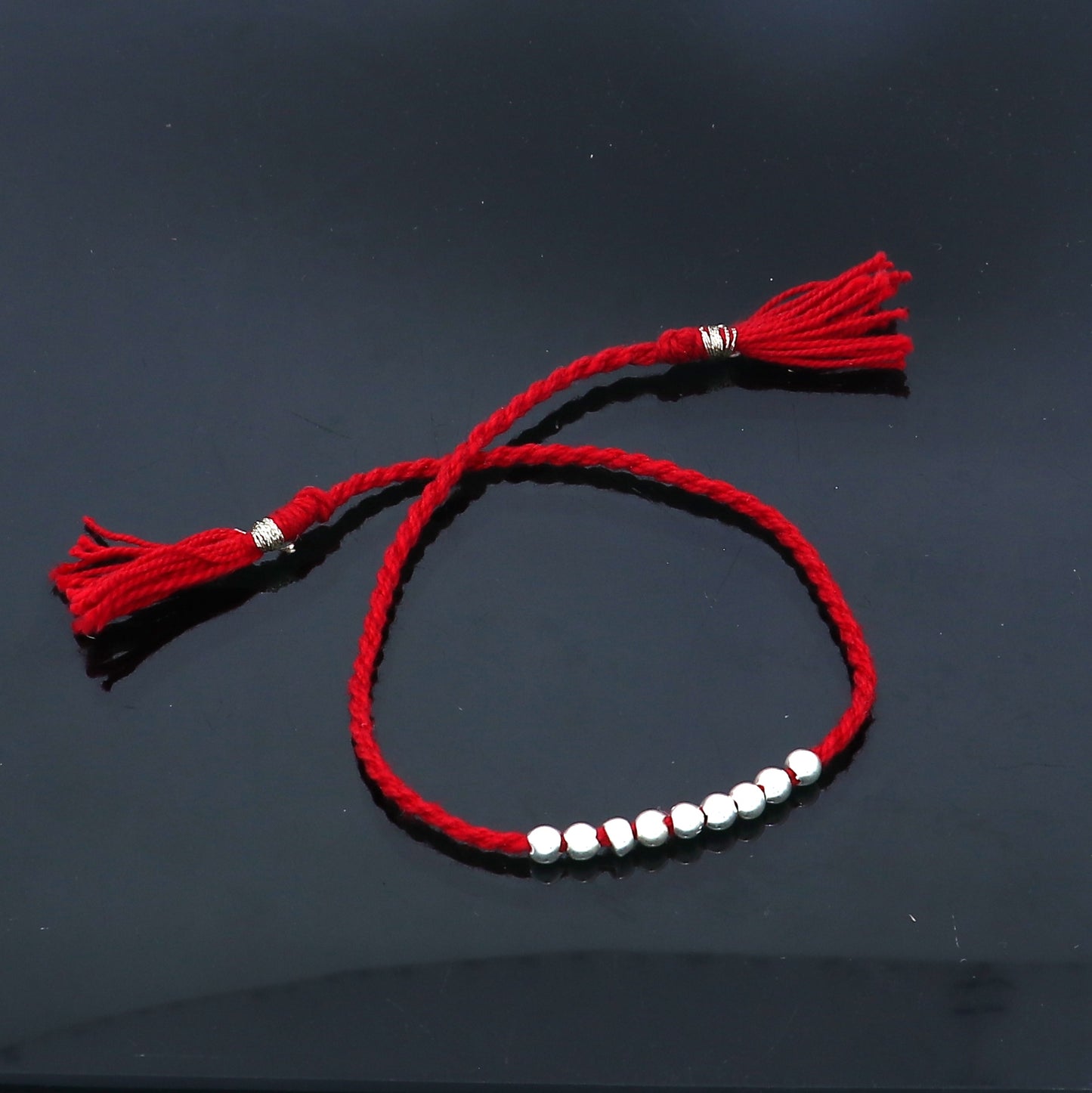 Sterling silver ball design thread rakhi bracelet by TRIBAL ORNAMENTS, featuring a detailed silver pendant for Rakshabandhan.