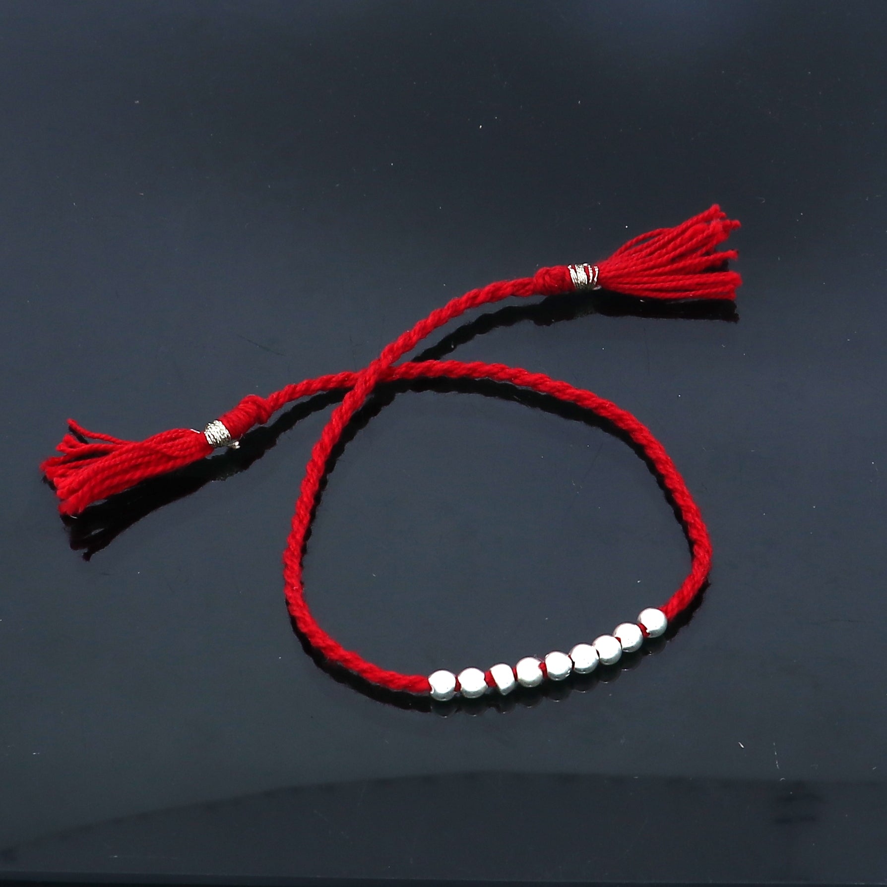Sterling silver ball design thread rakhi bracelet by TRIBAL ORNAMENTS, featuring a detailed silver pendant for Rakshabandhan.