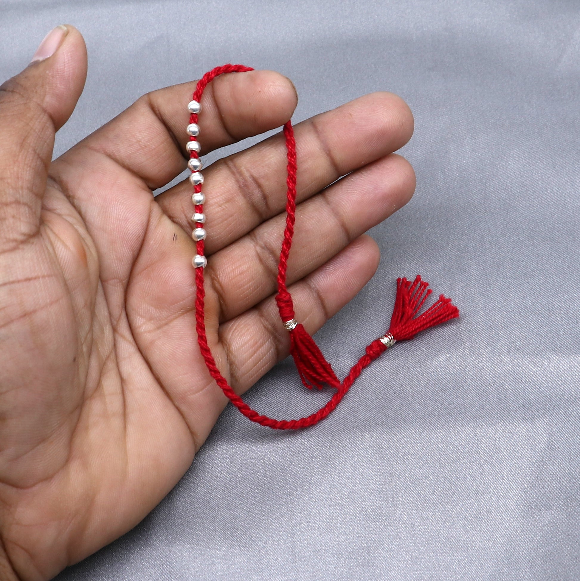 Sterling silver ball design thread rakhi bracelet by TRIBAL ORNAMENTS, featuring a silver pendant for Rakshabandhan festival.