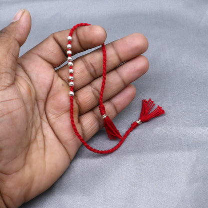 Sterling silver ball design thread rakhi bracelet by TRIBAL ORNAMENTS, featuring a silver pendant for Rakshabandhan festival.