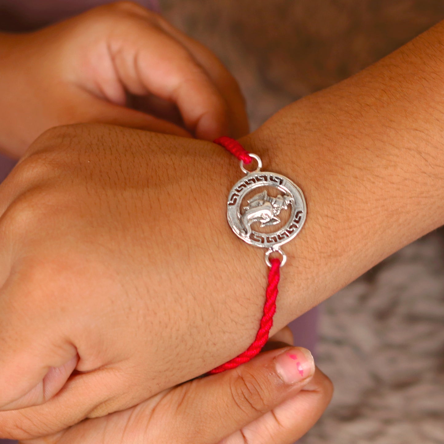 Sterling silver Ganesha design thread bracelet with red thread from TRIBAL ORNAMENTS, featuring a detailed elephant pendant.