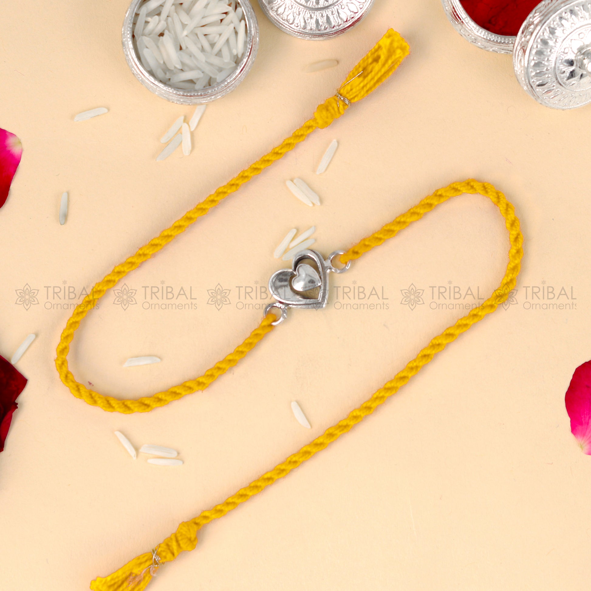 Sterling silver heart design thread rakhi bracelet by TRIBAL ORNAMENTS with red thread and silver heart pendant.