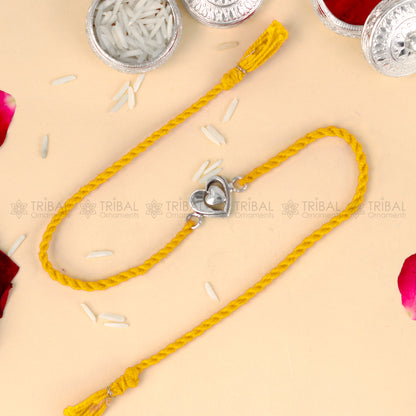 Sterling silver heart design thread rakhi bracelet by TRIBAL ORNAMENTS with red thread and silver heart pendant.