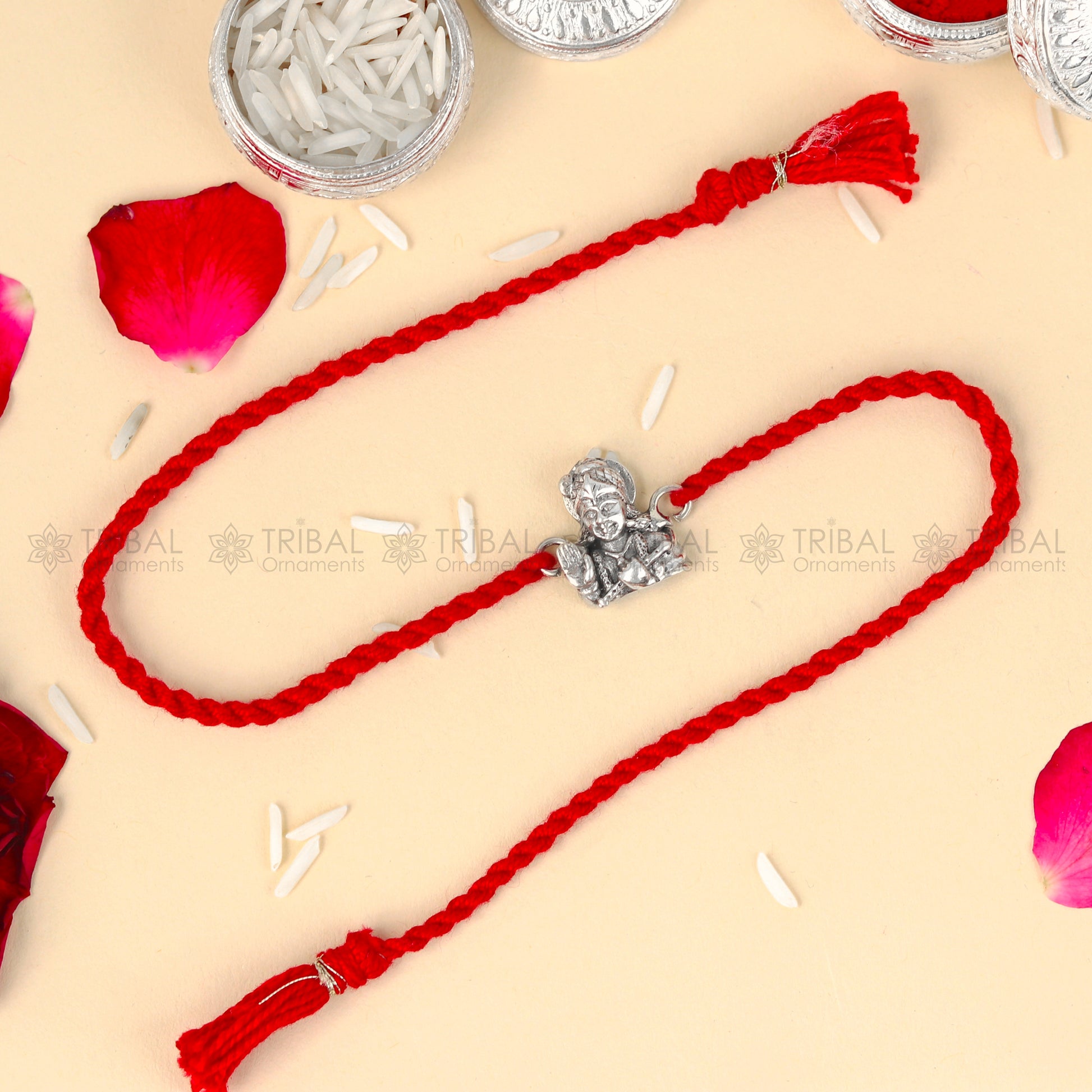 Sterling silver Lord Krishna design thread rakhi bracelet with red thread from TRIBAL ORNAMENTS, featuring intricate pendant detail.