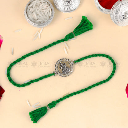 Sterling silver Lord Laxmi ji design thread rakhi bracelet with red thread from TRIBAL ORNAMENTS featuring a decorative pendant.