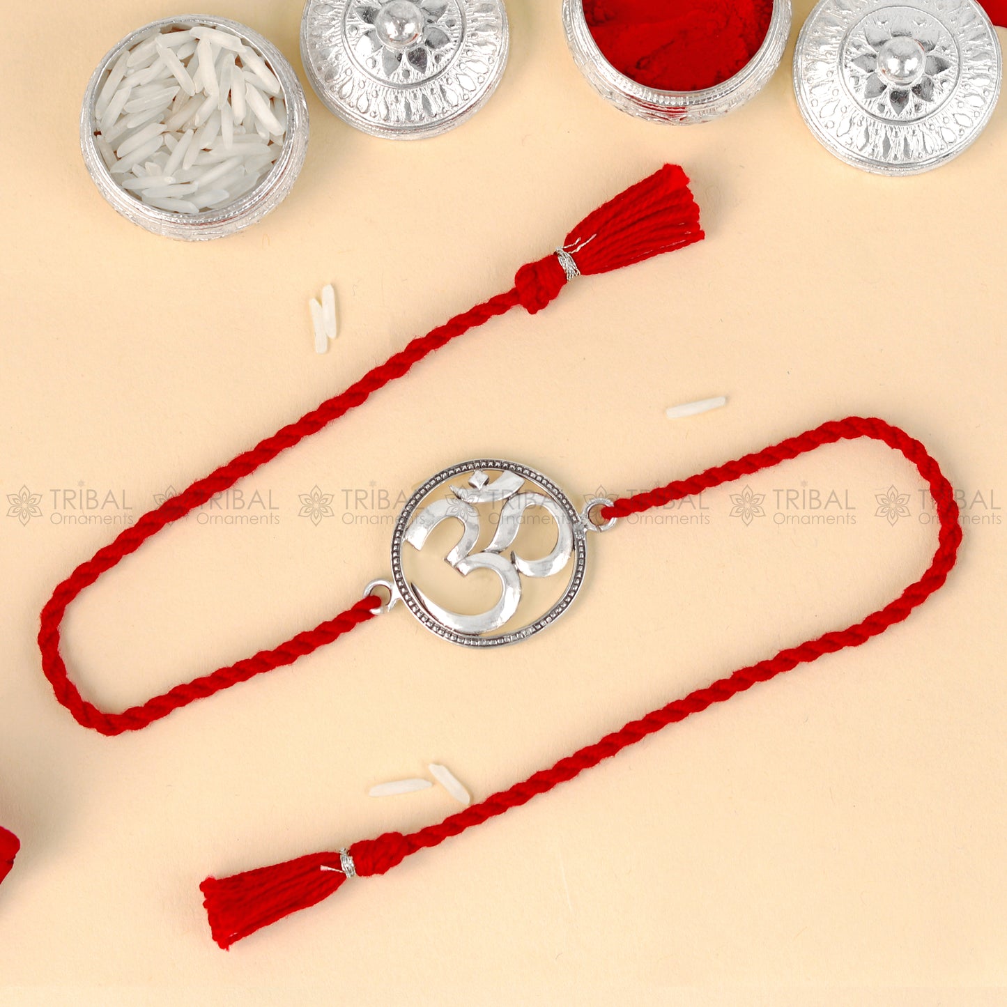 925 Sterling silver Om design thread rakhi bracelet with red thread from TRIBAL ORNAMENTS, featuring a detailed Om pendant.