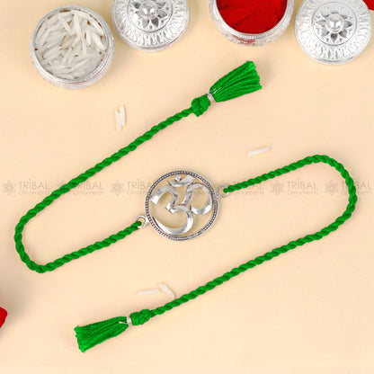Sterling silver Om design thread rakhi bracelet with red thread and silver pendant, handmade by TRIBAL ORNAMENTS.