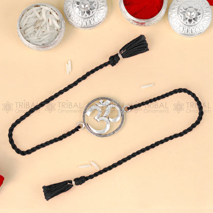 925 Sterling silver Om design thread rakhi bracelet with red thread from TRIBAL ORNAMENTS, featuring a detailed Om pendant.