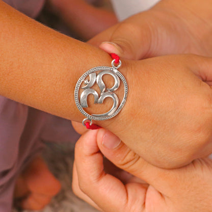 925 Sterling silver Om design thread rakhi bracelet with red thread and silver pendant, handcrafted by TRIBAL ORNAMENTS.
