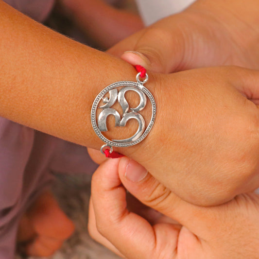 925 Sterling silver Om design thread rakhi bracelet with red thread and silver pendant, handcrafted by TRIBAL ORNAMENTS.