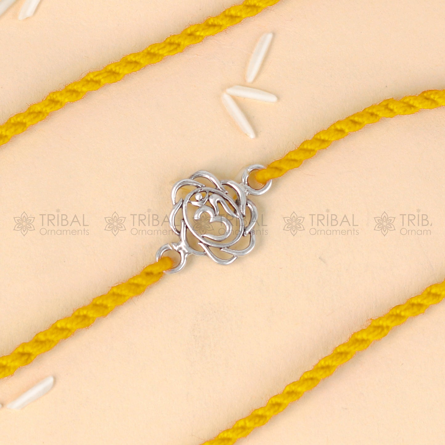 Sterling silver OM design thread rakhi bracelet with red thread from TRIBAL ORNAMENTS, perfect for Rakshabandhan celebrations.