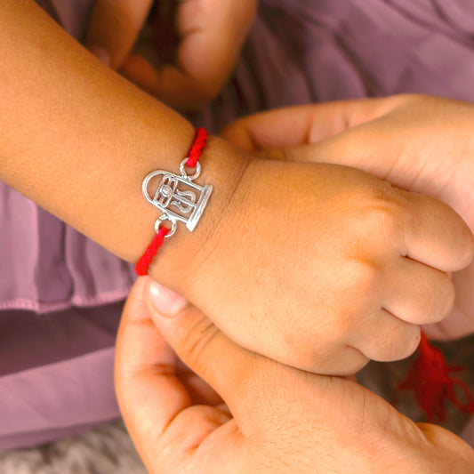 Sterling silver Siva lingam design thread rakhi bracelet with red thread and silver pendant from TRIBAL ORNAMENTS.