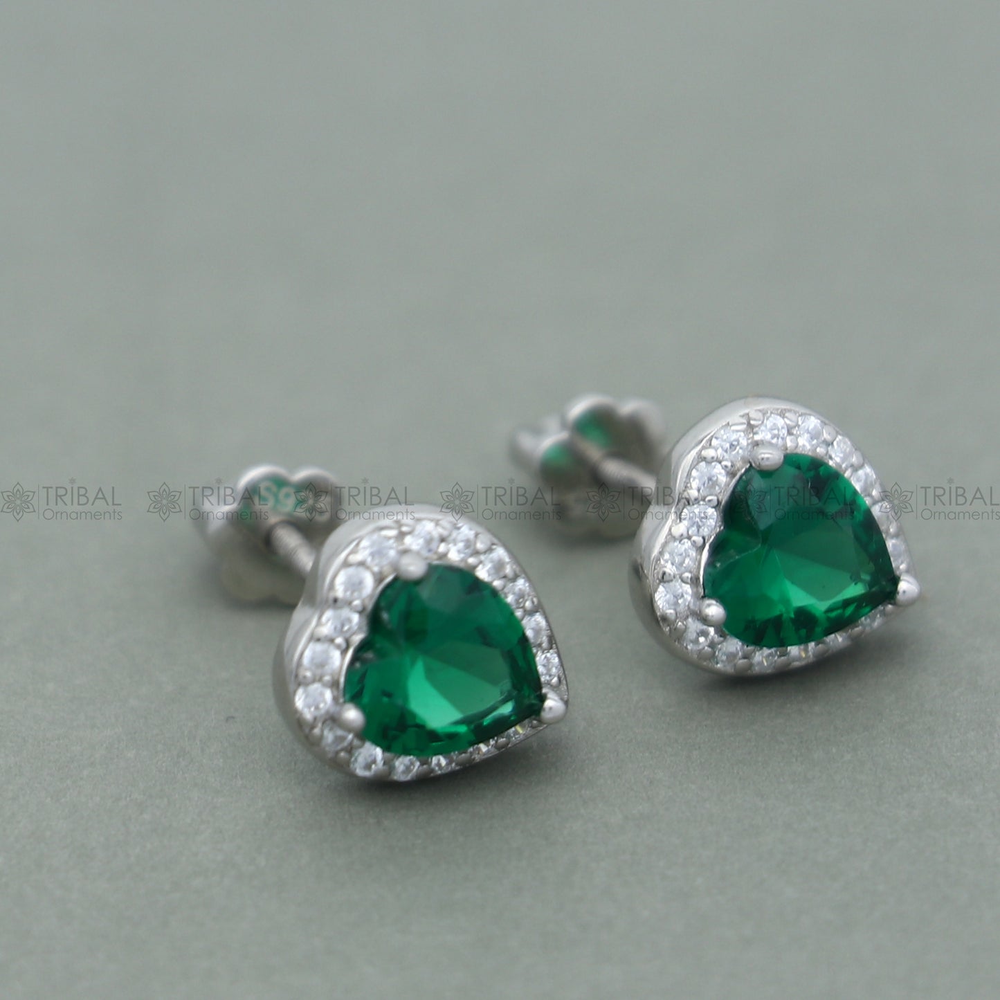 Sterling silver heart-shaped pendant set with green emerald diamond from TRIBAL ORNAMENTS, showcasing a detailed jewelry design.