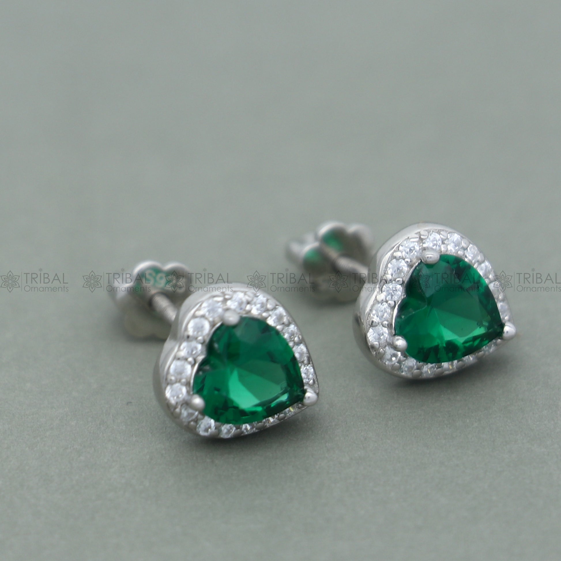 Sterling silver heart-shaped pendant set with green emerald diamond from TRIBAL ORNAMENTS, showcasing a detailed jewelry design.
