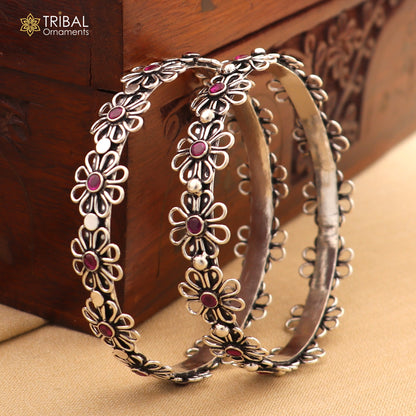 Sterling silver bangle bracelet with red stone flower design by TRIBAL ORNAMENTS, showcasing intricate craftsmanship and vibrant color.