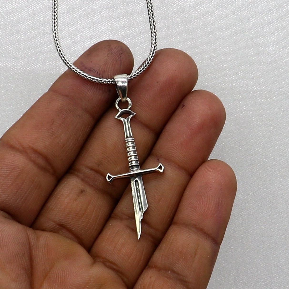 925 sterling silver small sword pendant by TRIBAL ORNAMENTS, handmade unisex jewelry with white finish and intricate design.
