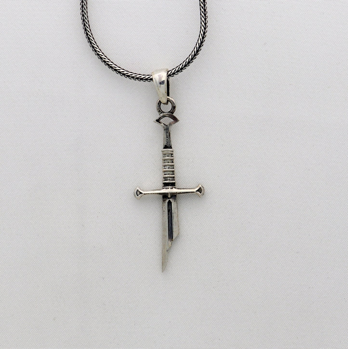 Sterling silver small sword pendant by Tribal Ornaments, handmade unisex jewelry with a white finish and intricate design.