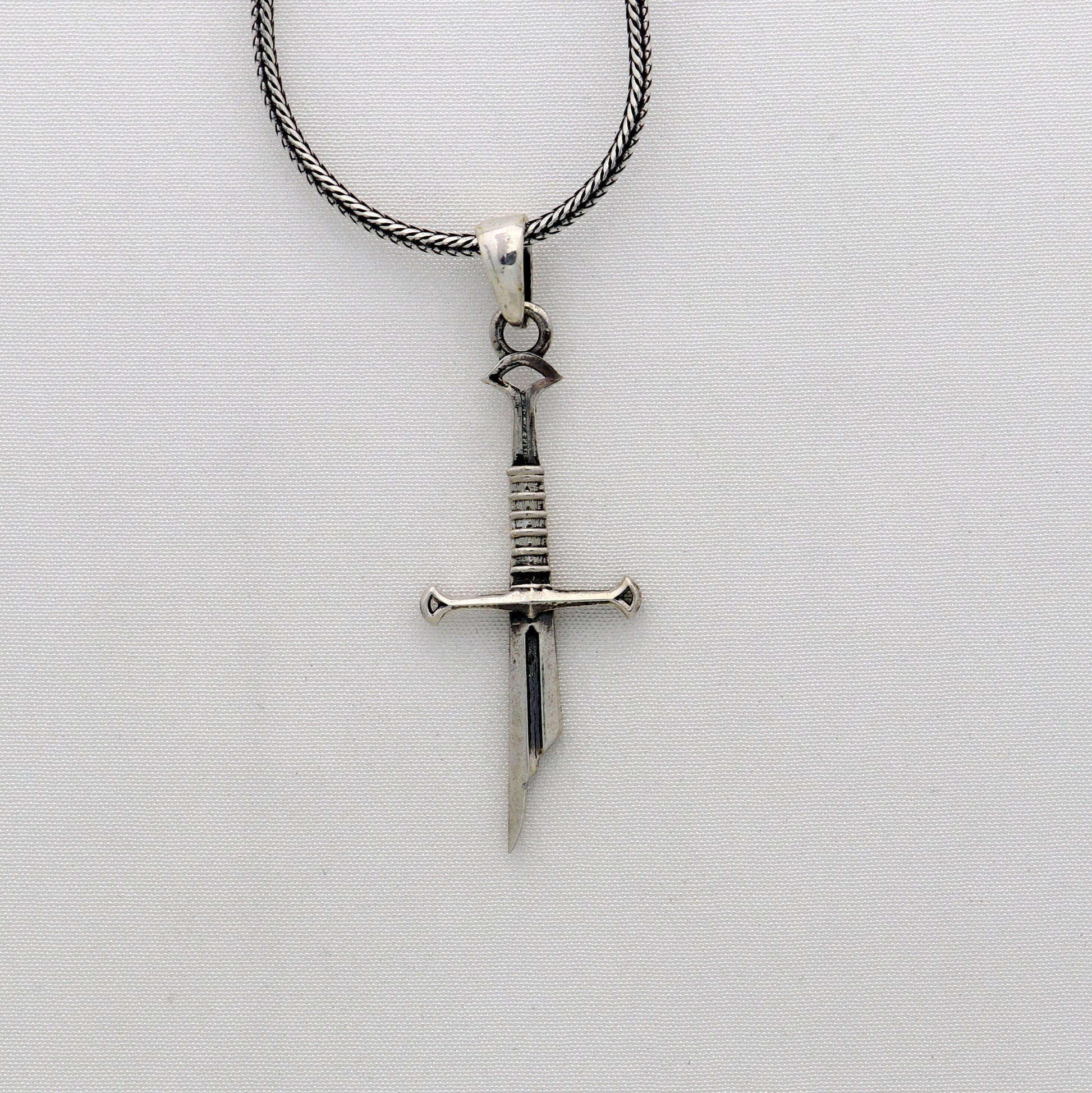Sterling silver small sword pendant by Tribal Ornaments, handmade unisex jewelry with a white finish and intricate design.