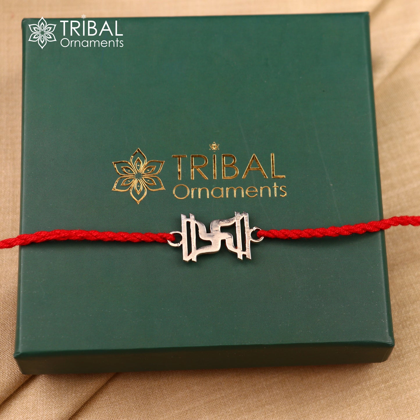 925 sterling silver Swastika rakhi with red thread, handcrafted by Tribal Ornaments, ideal for celebrating sibling bonds.