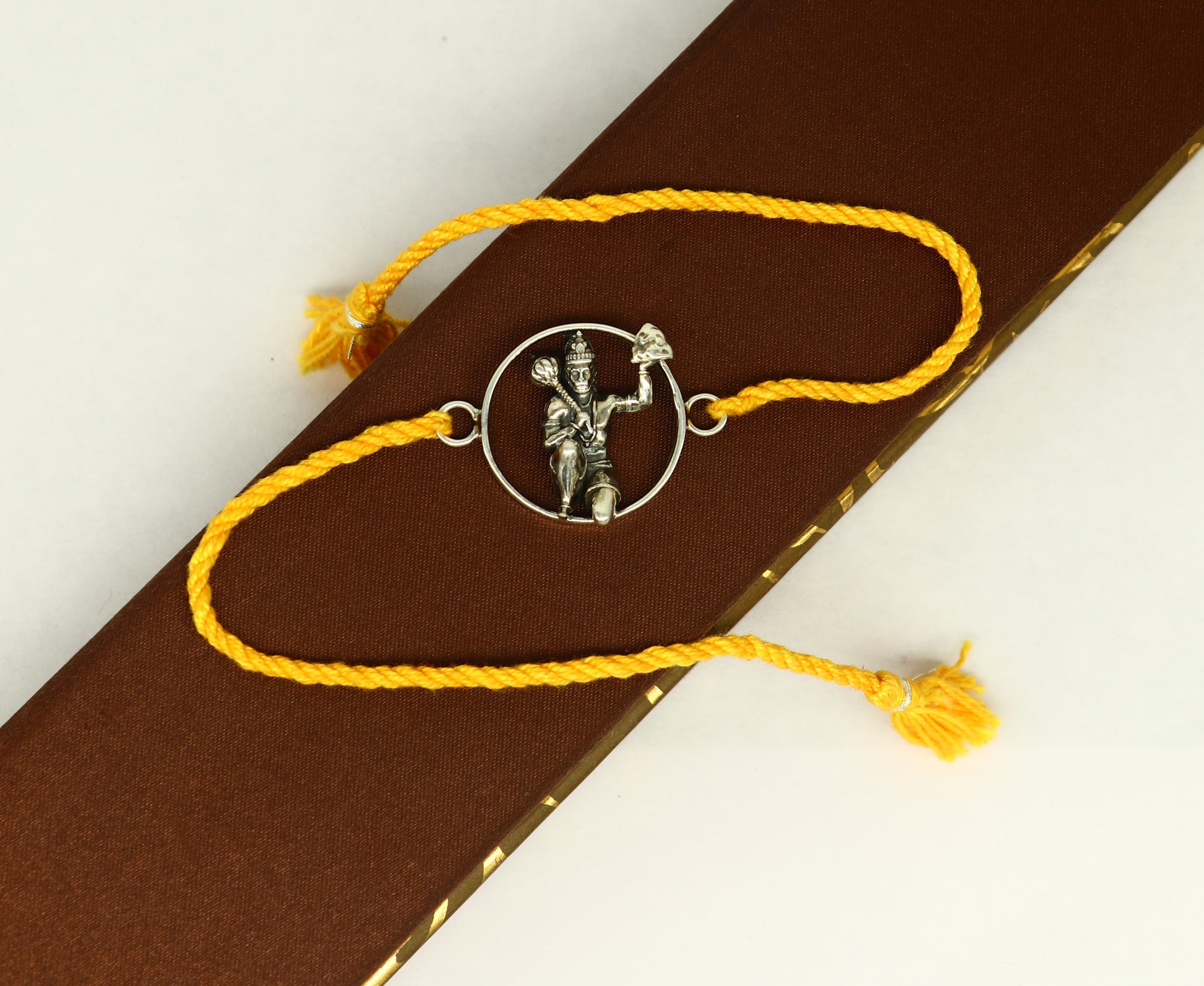 Sterling silver Hanuman idol bracelet with red thread rakhi, featuring intricate tribal design and craftsmanship from Tribal Ornaments.