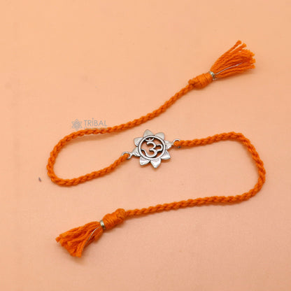 Sterling silver "AUM" mantra thread rakhi bracelet with red thread from Tribal Ornaments, featuring intricate silver detailing.